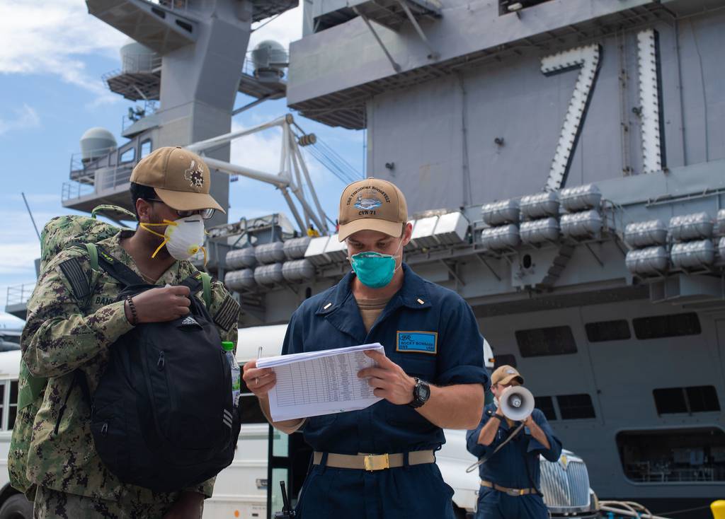 Ensign Rocky Bowman, right, checks Aviation Structural Mechanic 2nd Class Justin Banks into the aircraft carrier USS Theodore Roosevelt (CVN 71) May 16, 2020, after Banks completed off-base quarantine.