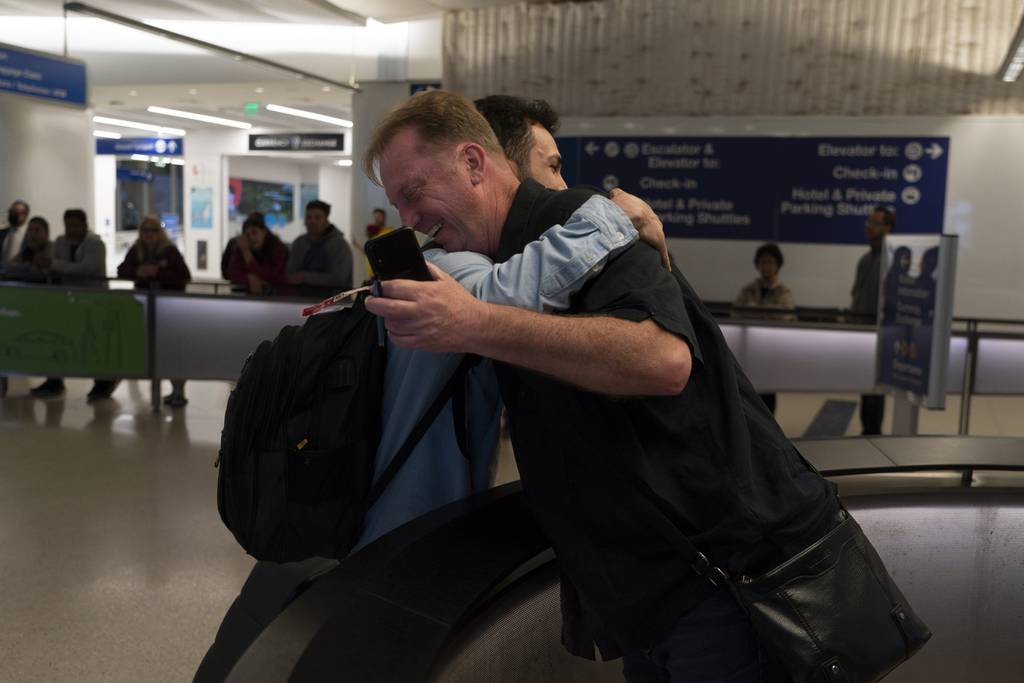 Michael White, a Navy veteran who was jailed in Iran for several years on spying charges, right, hugs Michael's former fellow prisoner and Iranian political activist Mahdi Vatankhah at the Los Angeles International Airport in Los Angeles, Thursday, June 1, 2023.