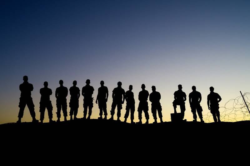 Airmen of the 332nd Air Expeditionary Wing pose for a group photo during sunrise after their shift at an undisclosed location on Aug. 15, 2020.