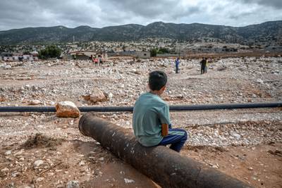 A boy watches as rescue teams search through the rubble in the eastern city of Soussa on Sept. 21, 2023, following deadly flash floods.