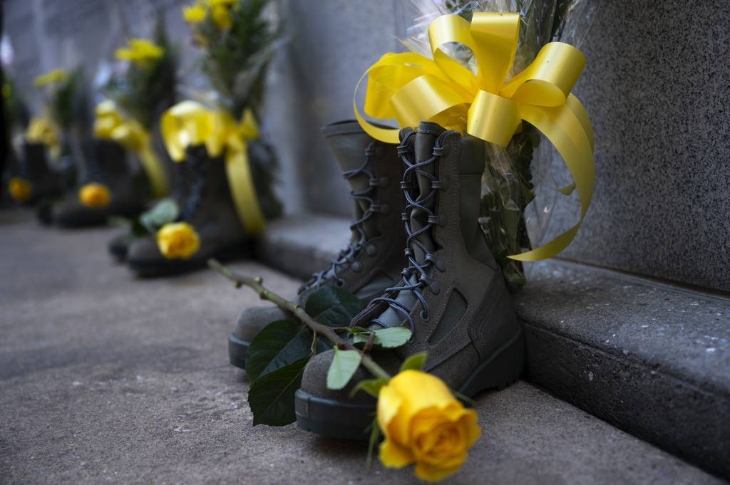 Combat boots and yellow flowers representing those who lost their lives are displayed during the Khobar Towers 25th Annual Memorial Ceremony, June 25, 2021, at Eglin Air Force Base, Florida.