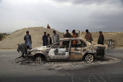 In this April 9, 2019, file photo, Afghans watch a civilian vehicle burnt after being shot by U.S. forces following an attack near the Bagram Air Base, north of Kabul, Afghanistan.