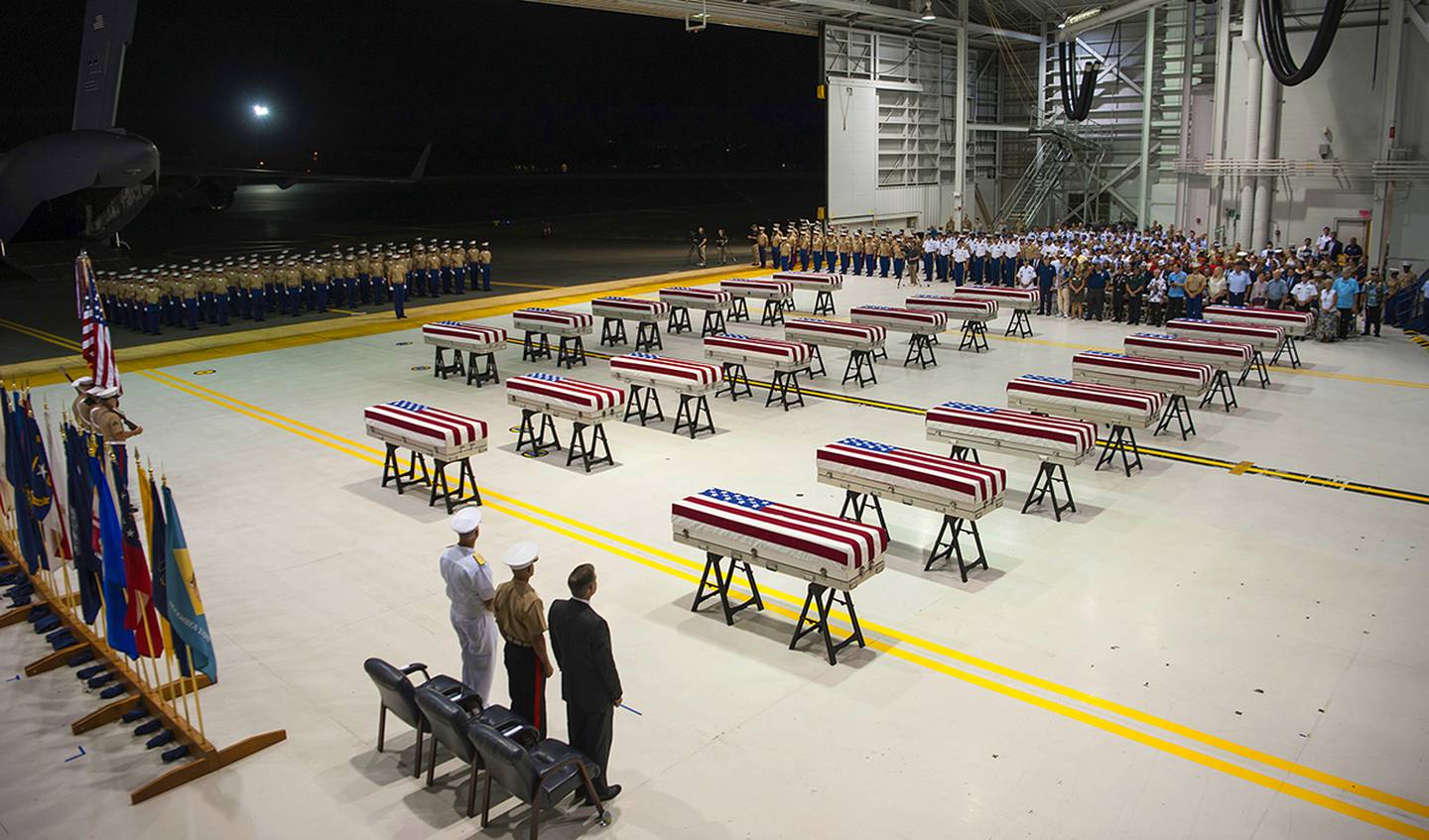 In this Wednesday, July 17, 2019 photo, service members and guests stand as "Taps" is played over transfer cases carrying the possible remains of unidentified service members lost in the Battle of Tarawa during World War II in a hangar at Joint Base Pearl Harbor-Hickam in Hawaii.