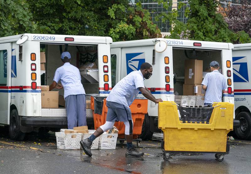 In this July 31, 2020, file photo, letter carriers load mail trucks for deliveries at a U.S. Postal Service facility in McLean, Va.