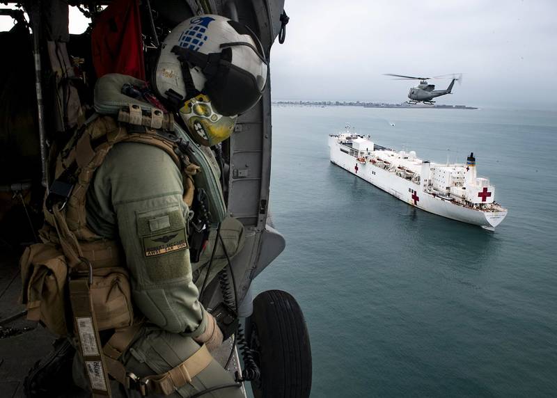 Naval Aircrewman (Helicopter) 1st Class Robert P. McCann flies in an MH-60S Sea Hawk helicopter alongside a Peruvian military Bell 412 on July 21, 2019, over the hospital ship USNS Comfort (T-AH 20).