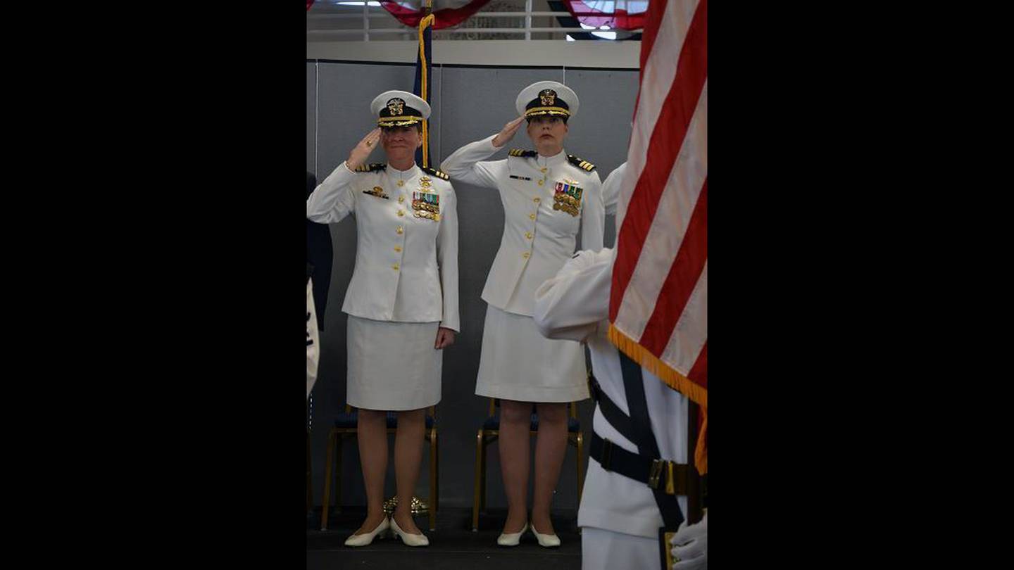 Outgoing Helicopter Training Squadron Eight (HT-8) commanding officer Cmdr. Jessica Parker and incoming HT-8 commanding officer Cmdr. Lena Kaman salute colors during the national anthem