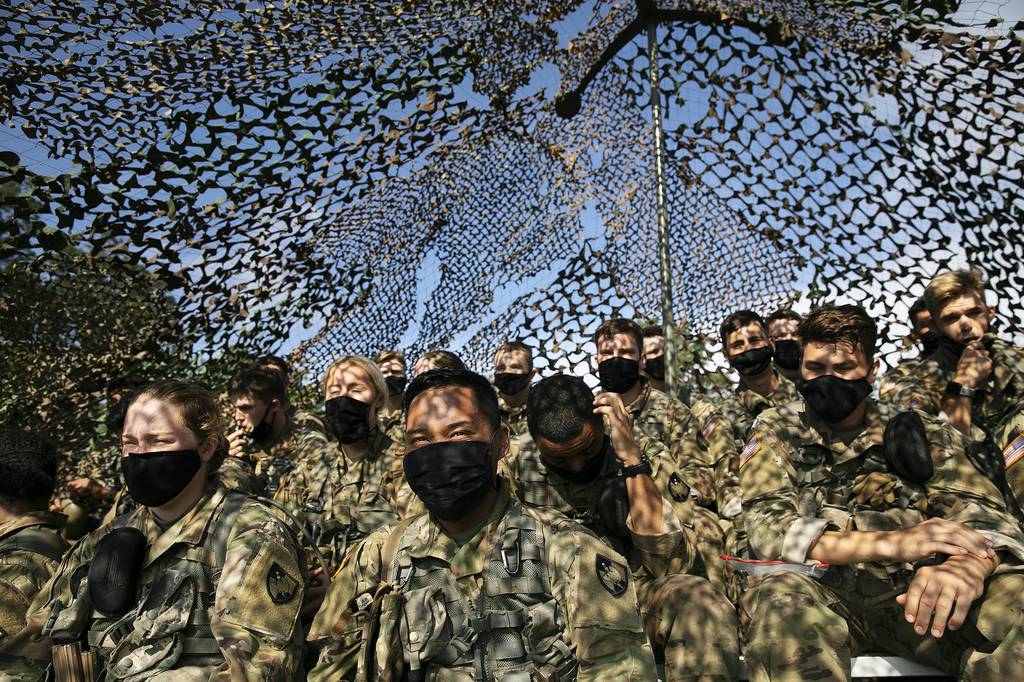 Cadets wear masks as they sit under camouflage netting, Friday, Aug. 7, 2020, in West Point, N.Y.