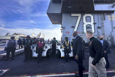 Defense Secretary Lloyd Austin, front left, walks next to the commanding officer of the USS Gerald R. Ford, Navy Capt. Rick Burgess, front, during an unannounced visit to the ship on Wednesday, Dec. 20, 2023.