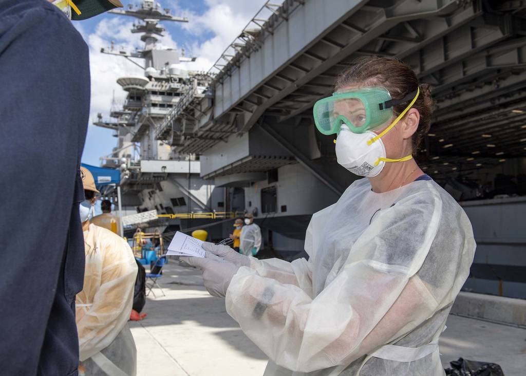 Cmdr. Brianna Rupp, a preventative medicine physician from the Navy and Marine Corps Public Health Center, takes a survey from a U.S. sailor assigned to the aircraft carrier Theodore Roosevelt (CVN 71) on April 22, 2020, in Apra, Guam, as part of a public health outbreak investigation.