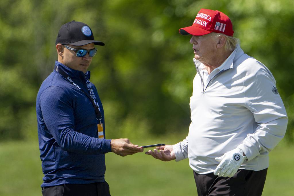 Walt Nauta, left, takes a phone from Former President Donald Trump during the LIV Golf Pro-Am at Trump National Golf Club, Thursday, May 25, 2023, in Sterling, Va.