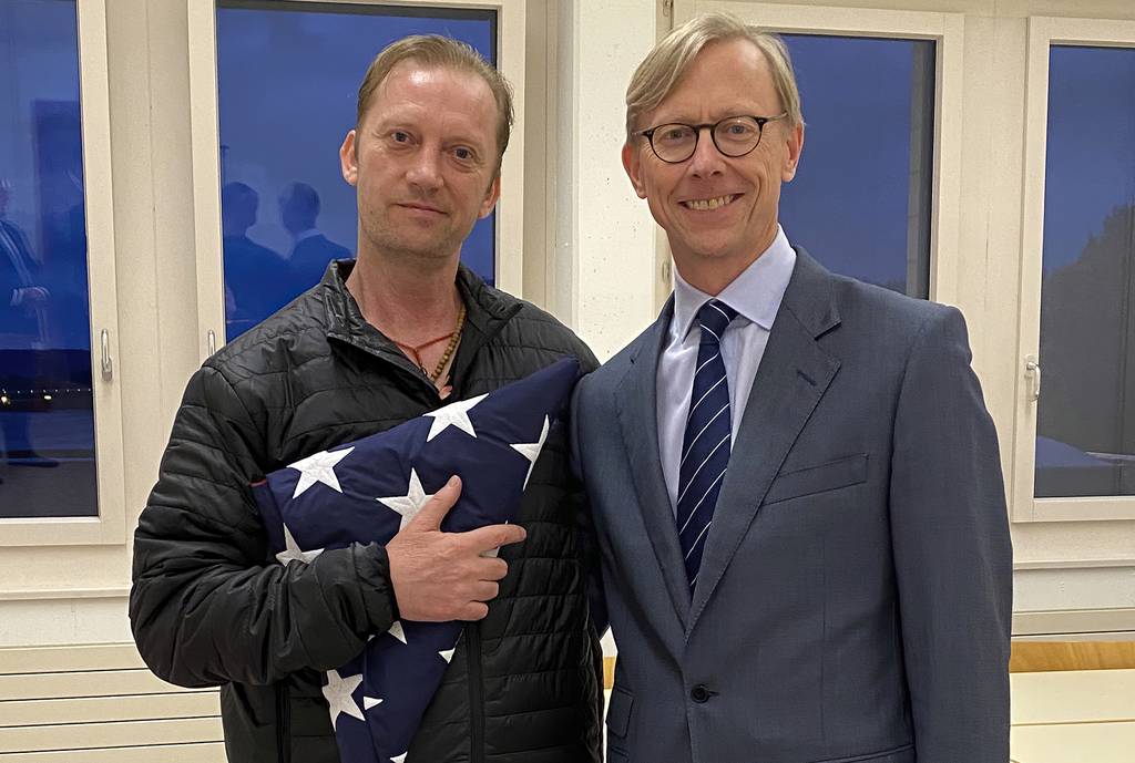 In this image provided by the U.S. State Department, Michael White holds an American flag as he poses for a photo Thursday, June 4, 2020, with U.S. special envoy for Iran Brian Hook at the Zurich, Switzerland, airport after White’s release from Iran.