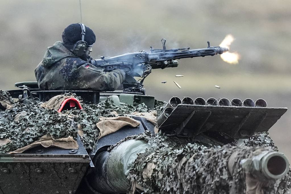 A soldier fires a machine gun from a Leopard 2 tank at the Bundeswehr tank battalion 203 at the Field Marshal Rommel Barracks in Augustdorf, Germany, Wednesday, Feb. 1, 2023.