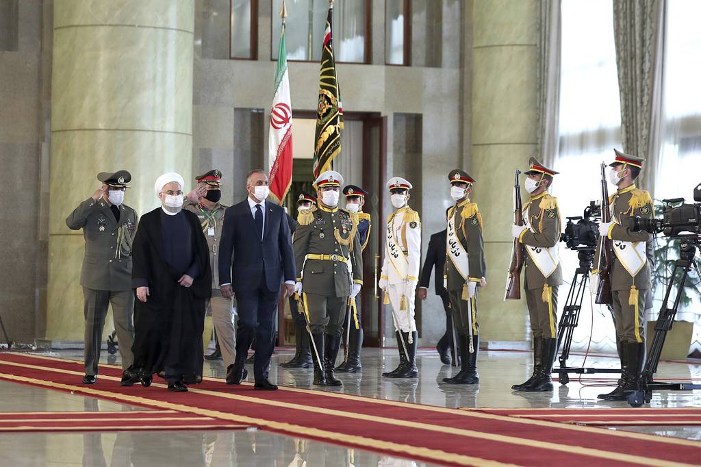 Iraqi Prime Minister Mustafa al-Kadhimi, fourth left, reviews an honor guard as he is welcomed by President Hassan Rouhani, second left, as they all wear protective face masks to help prevent spread of the coronavirus, during an official arrival ceremony, in Tehran, Iran, Tuesday, July 21, 2020.