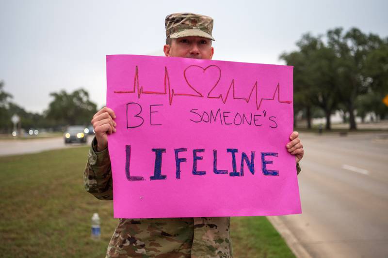 Civilian and military volunteers hold up signs showing appreciation to morning drivers on their way to work, Sept. 16, 2022.