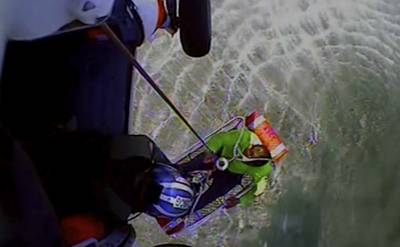 In this image taken from U.S. Coast Guard video, one of three fishermen is rescued from ocean waters by the Coast Guard five miles east of the island of Nantucket off the Cape Cod, Mass., coast Saturday, Aug. 5, 2023.