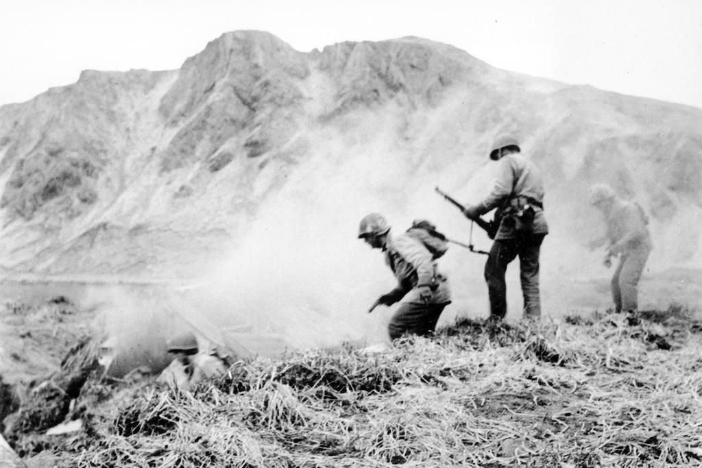 A U.S. squad armed with guns and hand grenades closes in on Japanese holdouts entrenched in dugouts during World War II on Attu Island, Alaska, in June 1943.