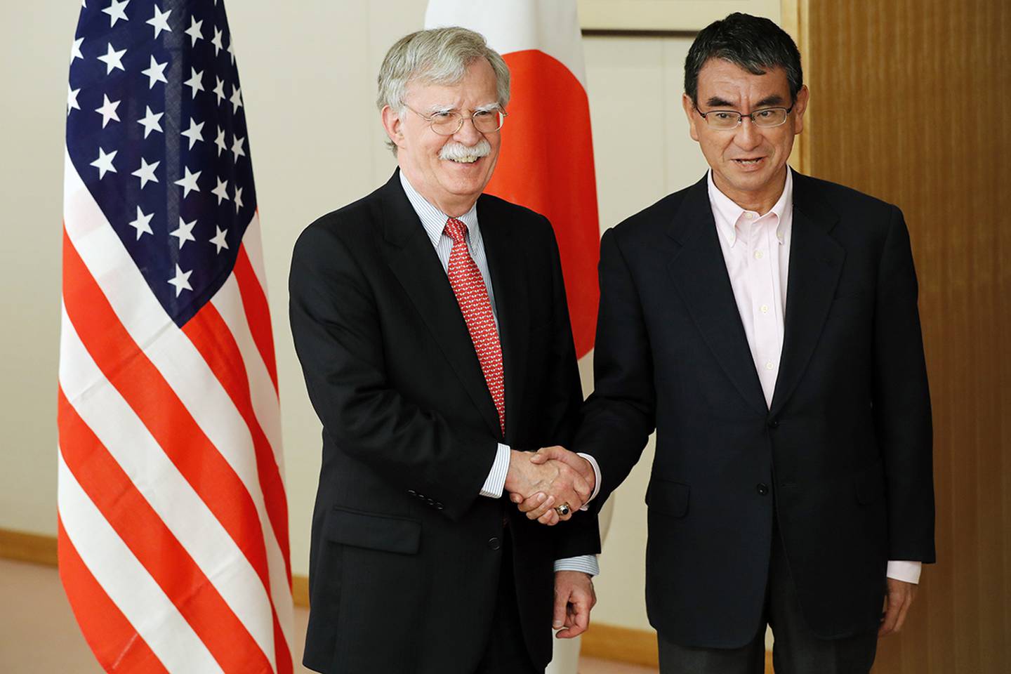Japanese Foreign Minister Taro Kono, right, and U.S. National Security Advisor John Bolton, left, shake hands prior to their meeting in Tokyo Monday, July 22, 2019.