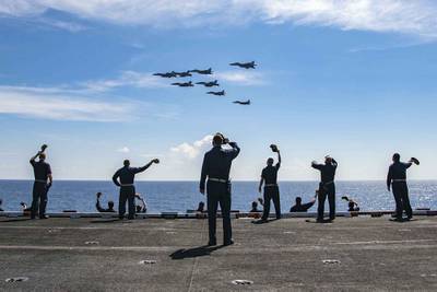 Master Chief David Conduff, command master chief of the aircraft carrier USS Nimitz (CVN 68), waves to four F-18's from the Nimitz and four MiG 29K Fulcrum K from the Indian navy aircraft carrier INS Vikramaditya (R 33) on Nov. 20, 2020, from the flight deck of the Nimitz while participating in Malabar 2020 in the Indian Ocean.