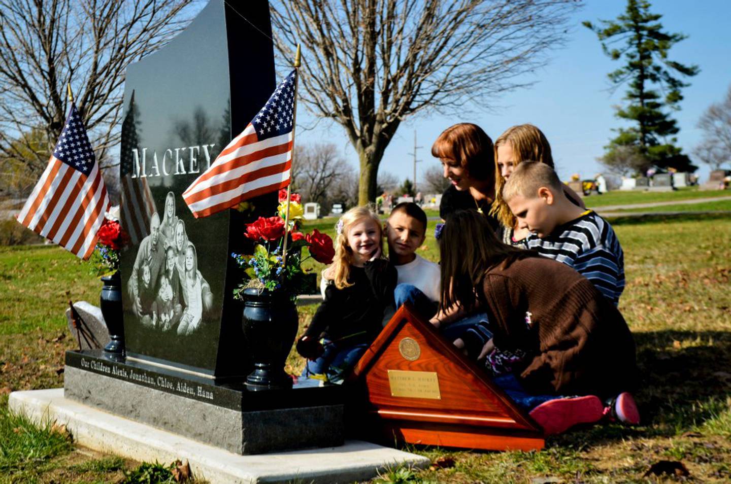 Kaanan Fugler, surviving spouse of Staff Sgt. Matthew Mackey, visits his grave with her children.