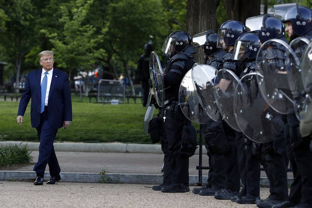 President Donald Trump walks past police in Lafayette Park after he visited outside St. John's Church across from the White House Monday, June 1, 2020, in Washington.