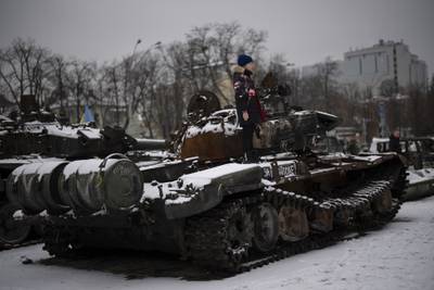 A boy stands on a destroyed Russian tank displayed in downtown Kyiv, Ukraine, Tuesday Jan. 31, 2023.
