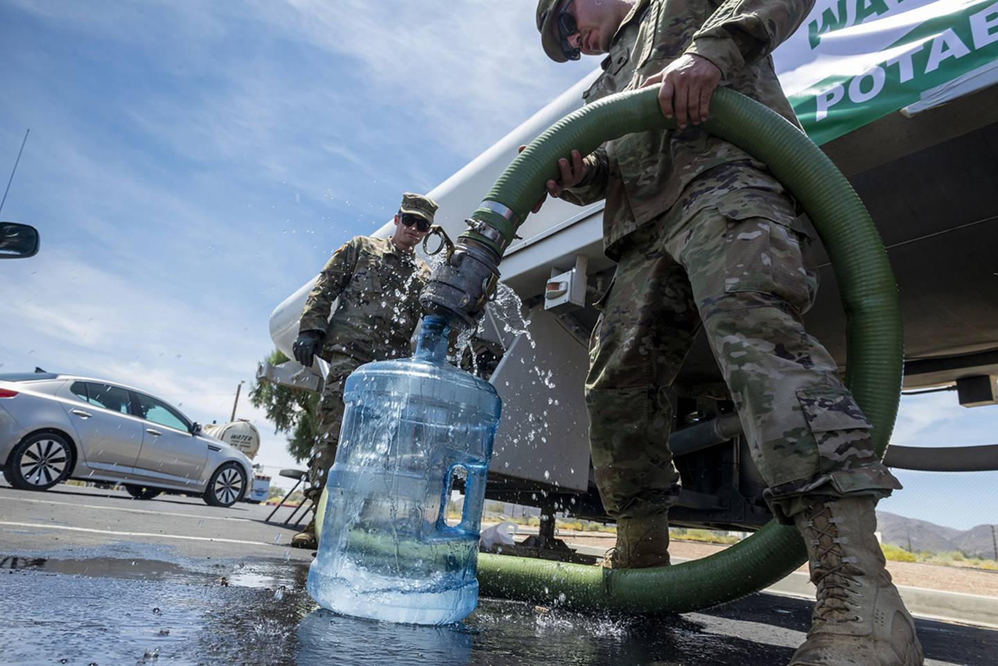 Pfc. Evan Siebuhr, left, and Pfc. Henry Marquez of the 670th Military Police fill water bottles for residents in Trona, Calif., on July 9, 2019.