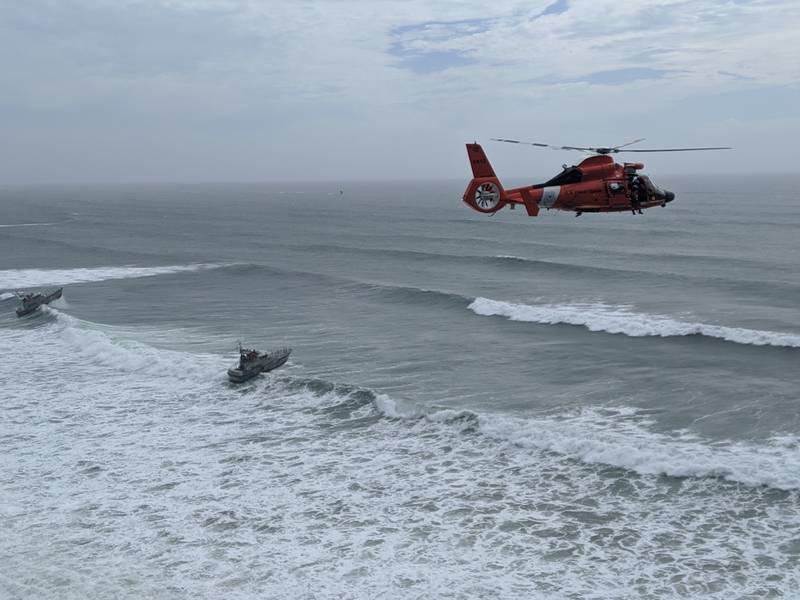 An aircrew aboard an MH-65 Dolphin helicopter from Air Facility Newport arrives on scene during the rescue of seven people trapped on the cliffs near Yaquina Head, Ore., May 29, 2020. Two Station Yaquina Bay boatcrews aboard 47-foot Motor Lifeboats were positioned offshore as a contingency.