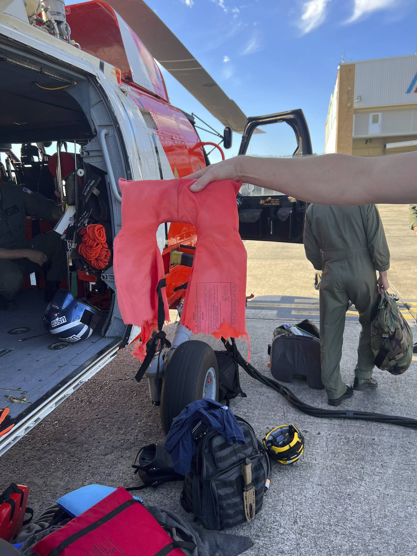 In this image provided by the Coast Guard, a Coast Guard Air Station New Orleans aircrew member holds up a torn life jacket from a recent rescue off the coast of Empire, La., on Oct. 9, 2022.