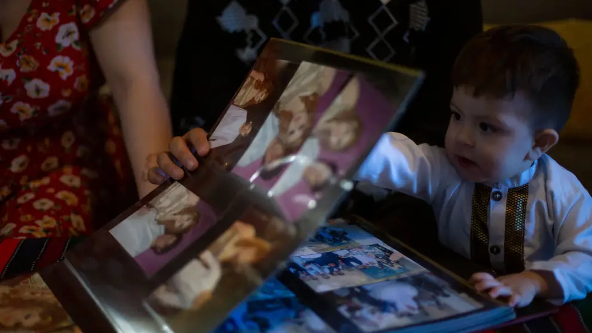 At their home in Austin, Azita Jawady, her husband Hamid Sadra and their 1-year-old son Qmars look through wedding photos from Afghanistan.