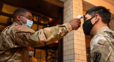 Pfc. Caleb Brisard takes a soldier’s 
temperature at the entrance of a local New York City hotel in support of the Department of Defense 
COVID-19