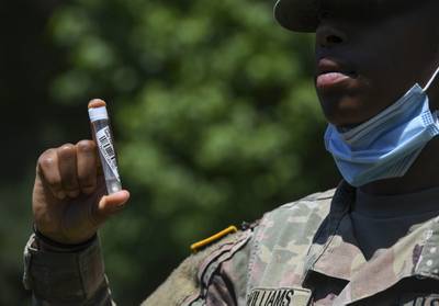 A U.S. Army soldier holds up a s mass rapid COVID-19 test sample during testing at Joint Base Langley-Eustis, Va., June 3, 2020.