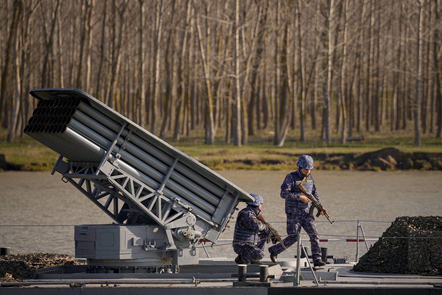 Servicemen walk on the deck of a warship sailing on the river Danube during a Romanian Navy led exercise outside Mahmudia, Romania, Thursday, March 30, 2023.