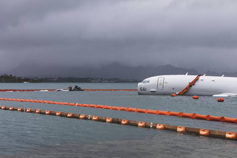 This Nov. 21, 2023, handout photo provided by the U.S. Marine Corps shows U.S. Navy sailors deploying temporary protective barriers around a downed Navy P-8A in waters just off the runway at Marine Corps Air Station Kaneohe Bay in Kaneohe Bay, Hawaii.